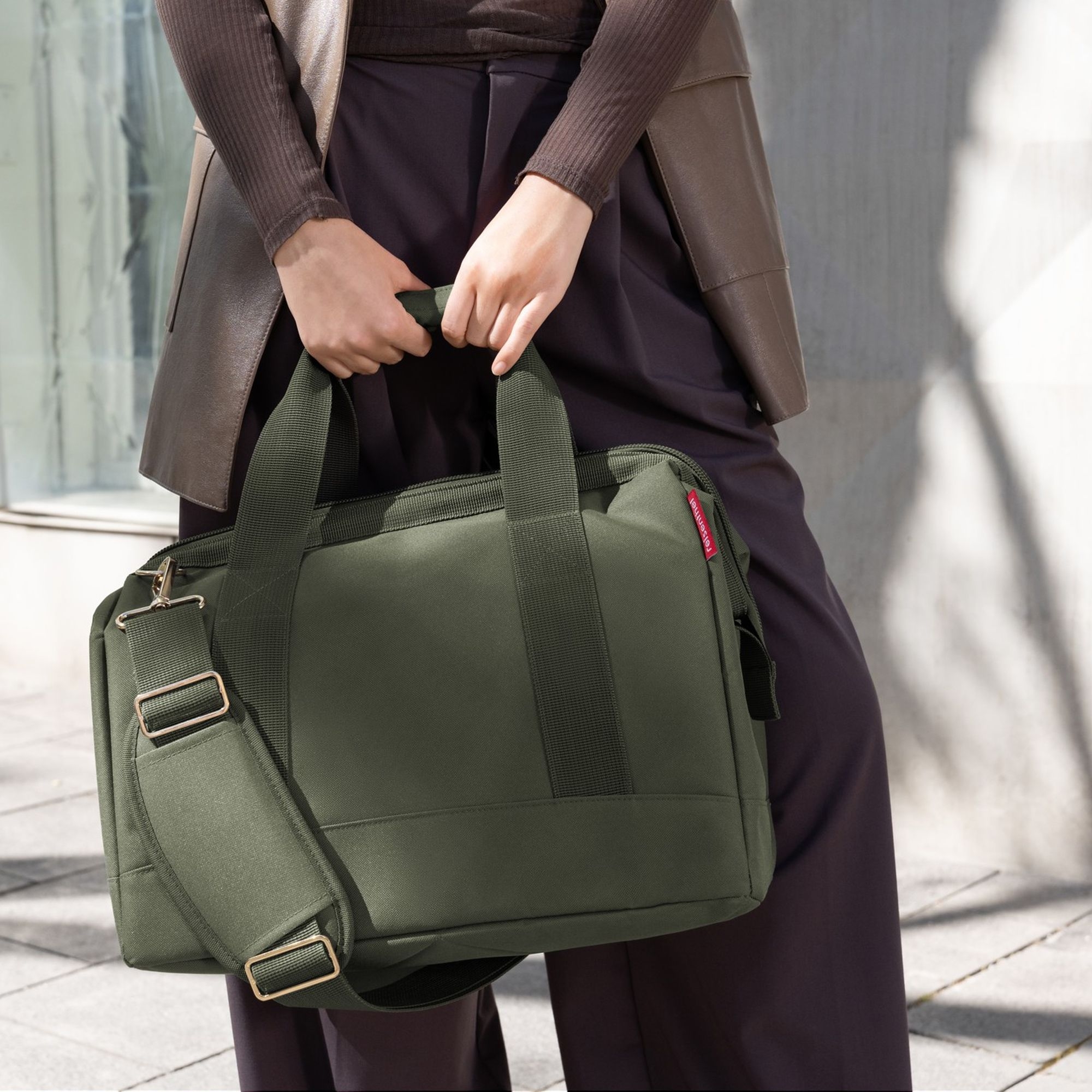 Person carrying olive green shoulder bag by hand