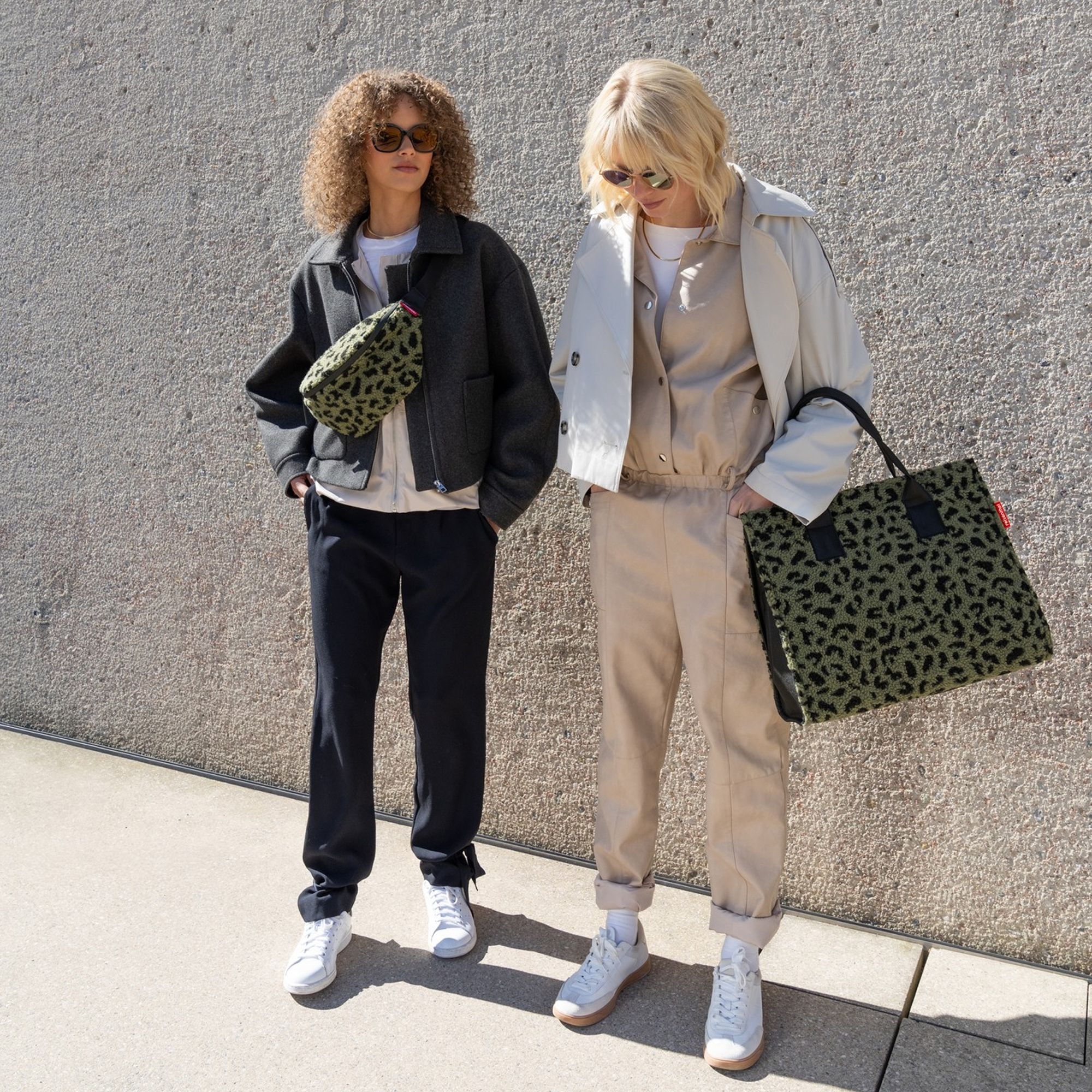 Two women wearing stylish green leopard print bags