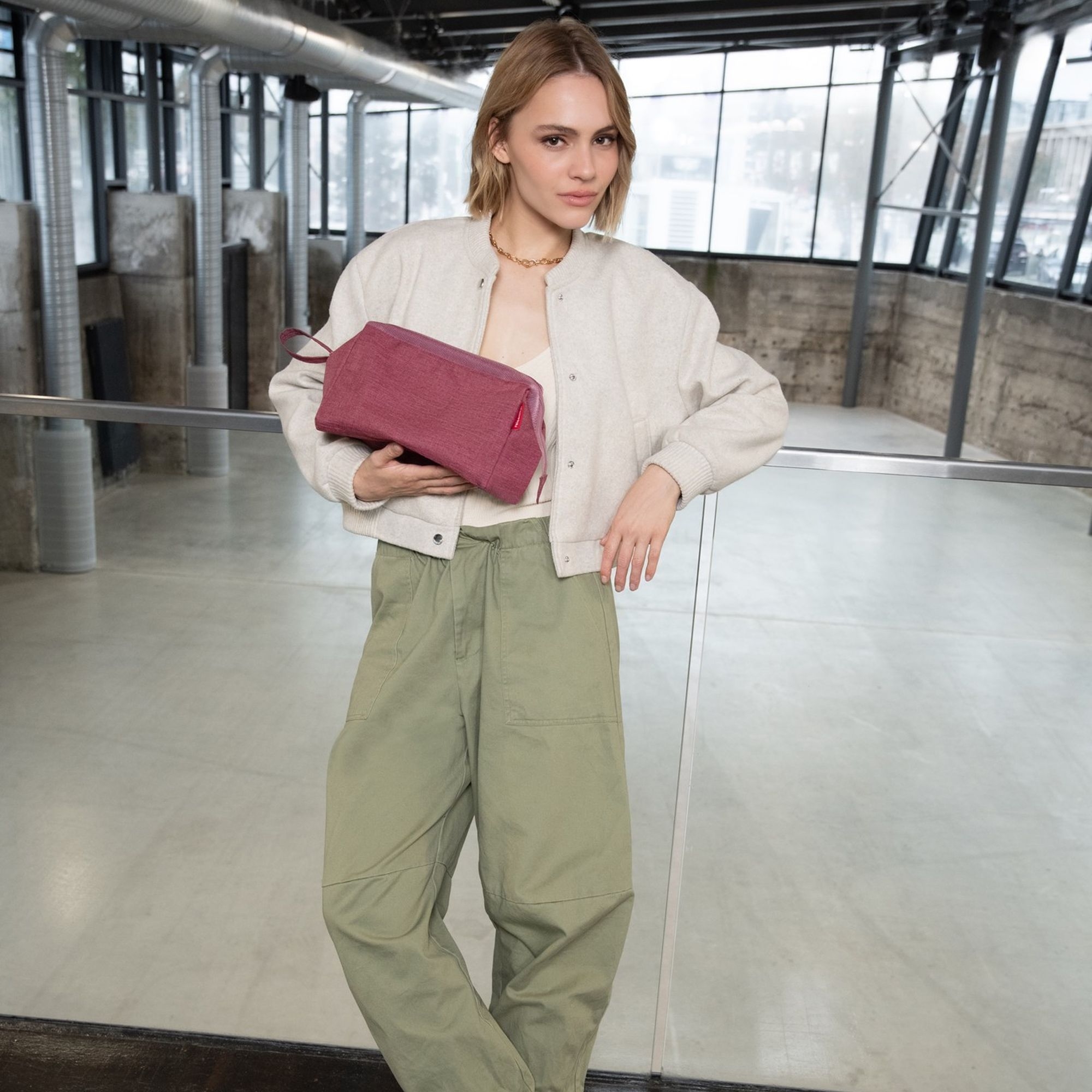 Woman holding pink toiletry bag in urban loft