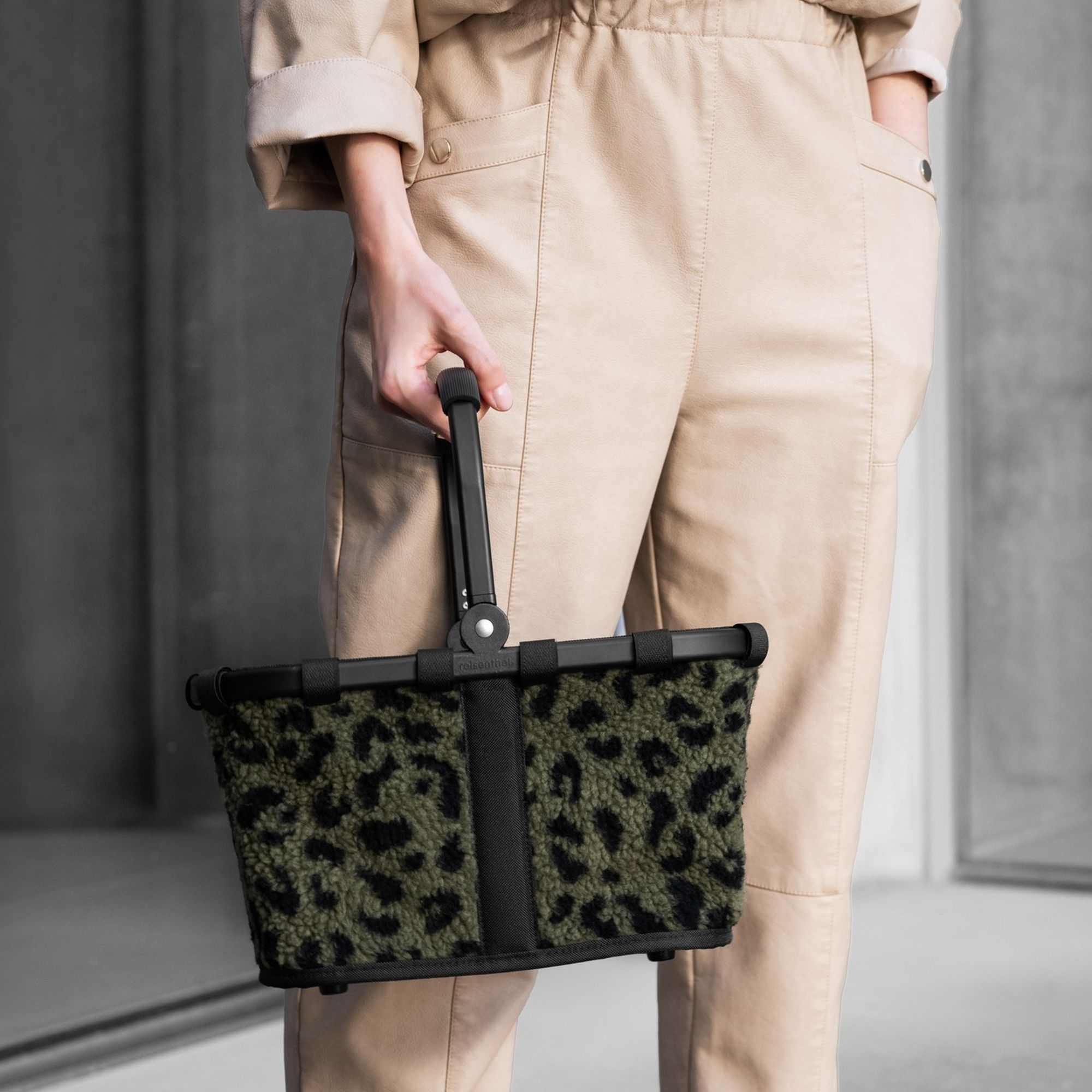 Person carrying green shopping basket with leopard fleece