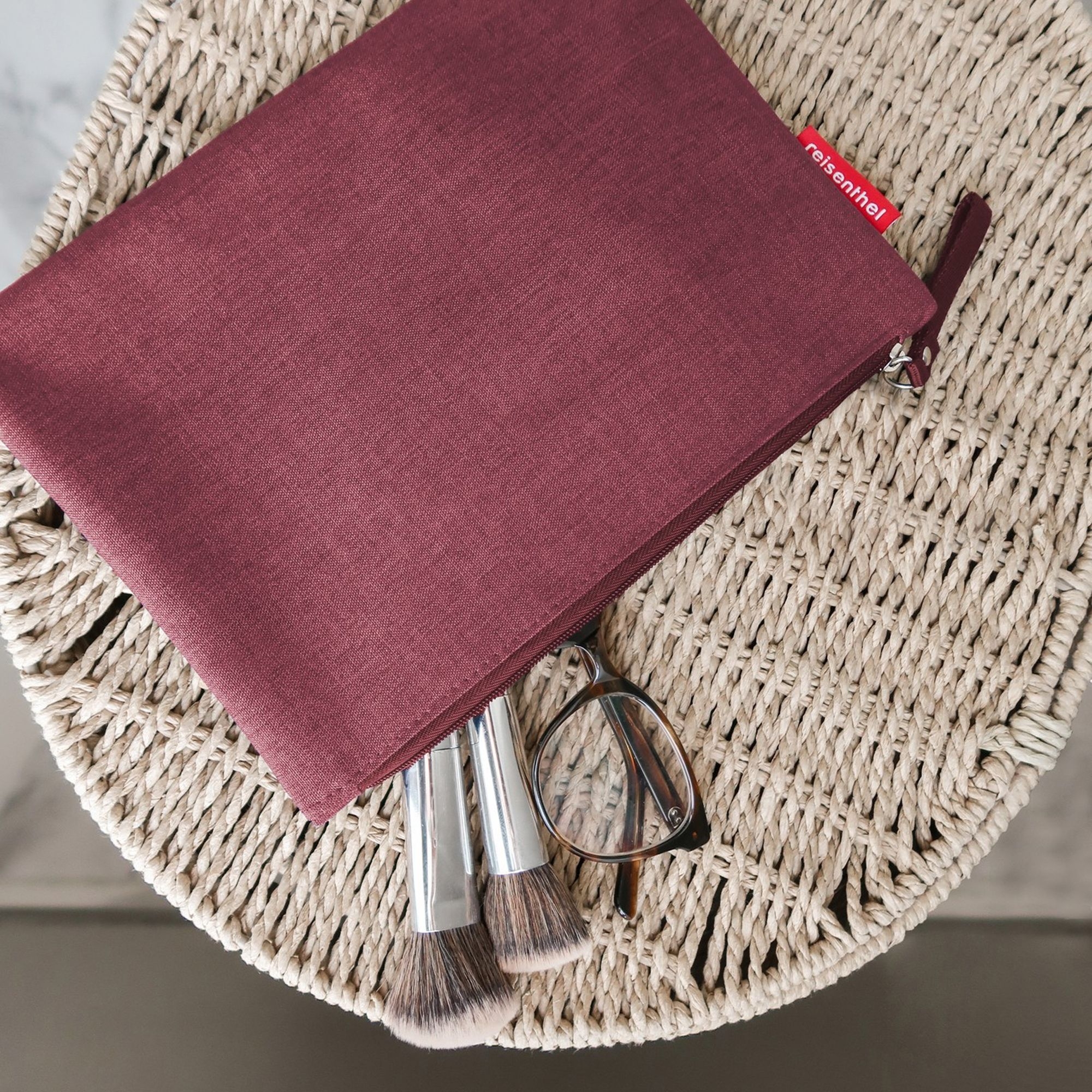 Burgundy cosmetic pouch with brushes and glasses