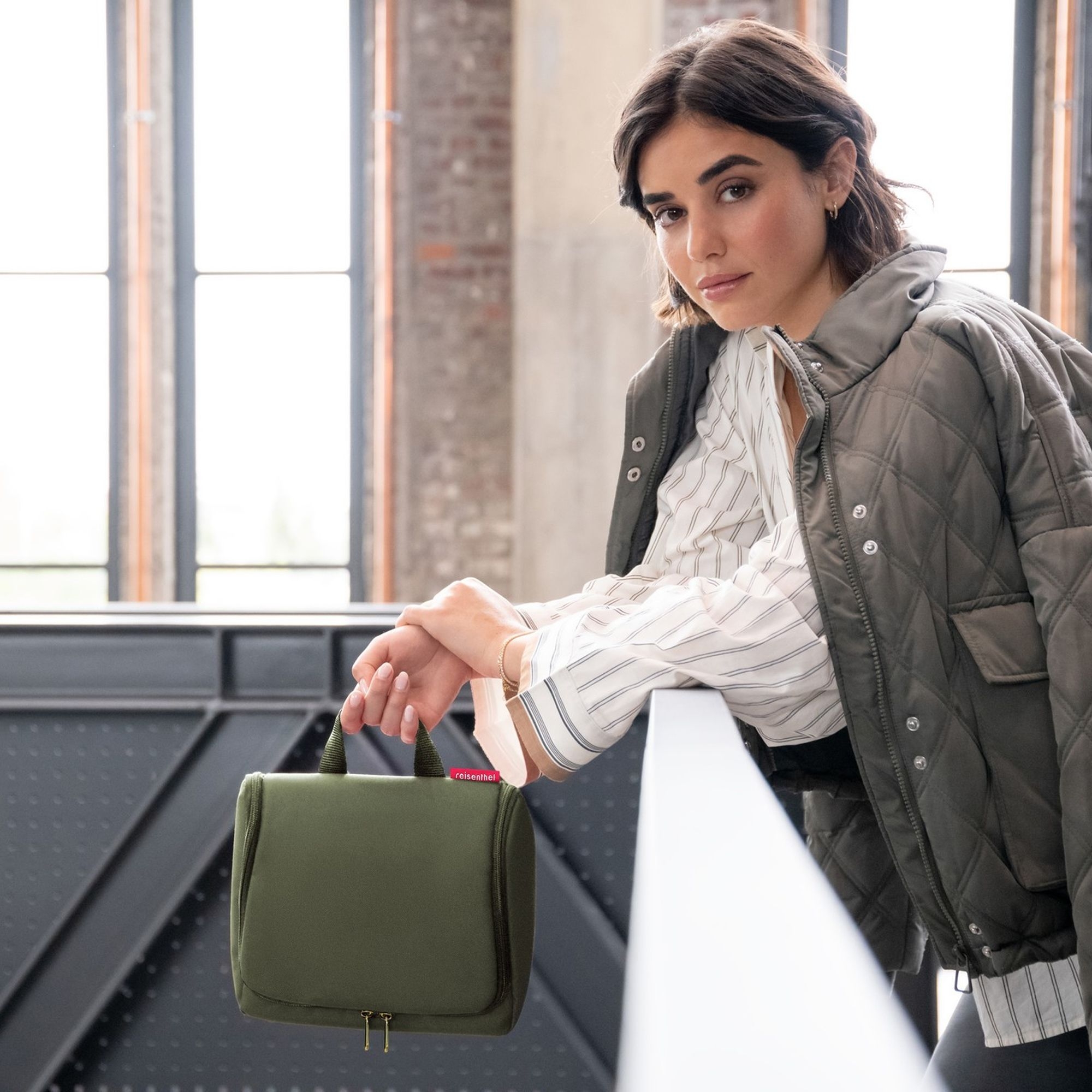 Woman holding an olive green toiletry bag