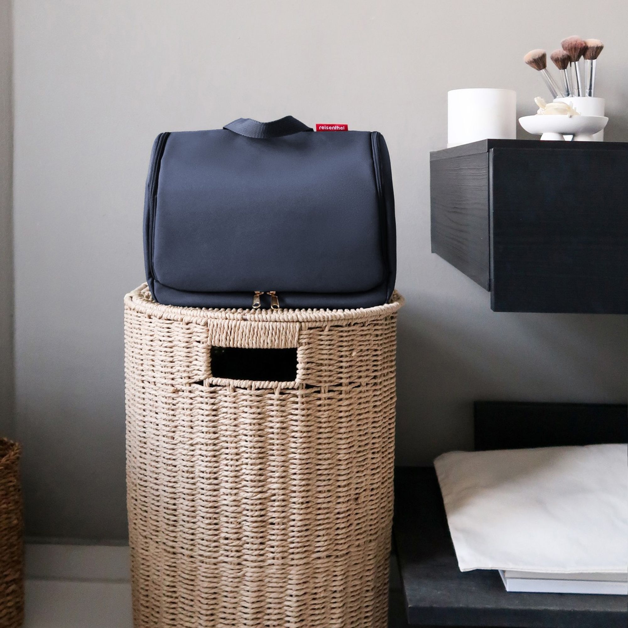 Dark blue toiletry bag on woven laundry basket