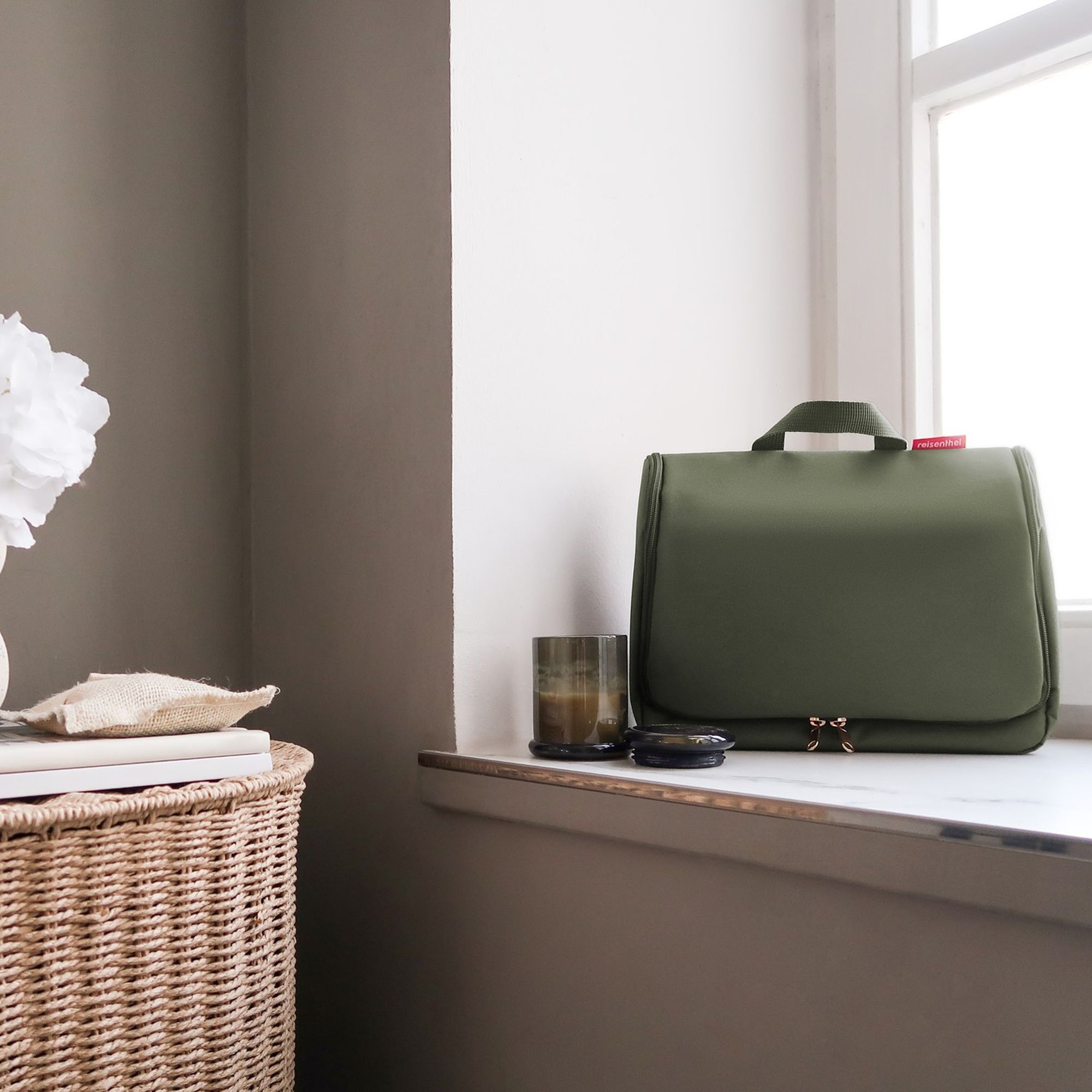 Practical green toiletry bag on bright windowsill