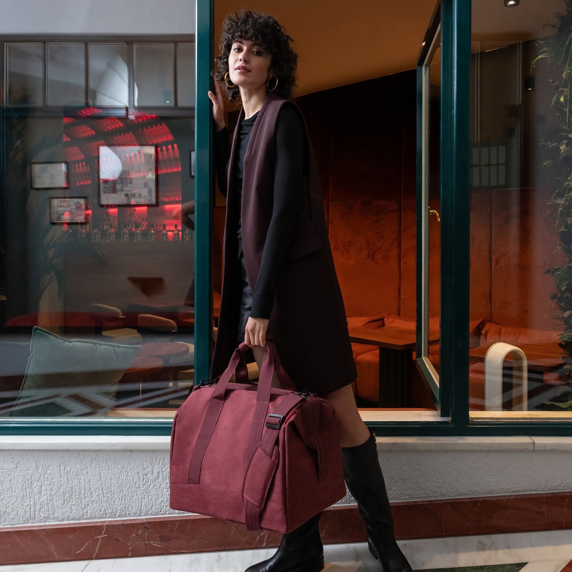 Woman with burgundy travel bag by stylish lounge