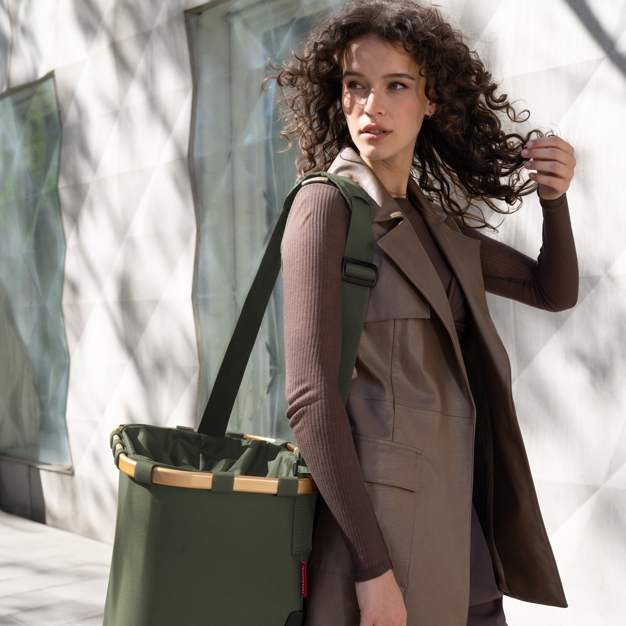 Woman carrying olive green shopping basket with strap
