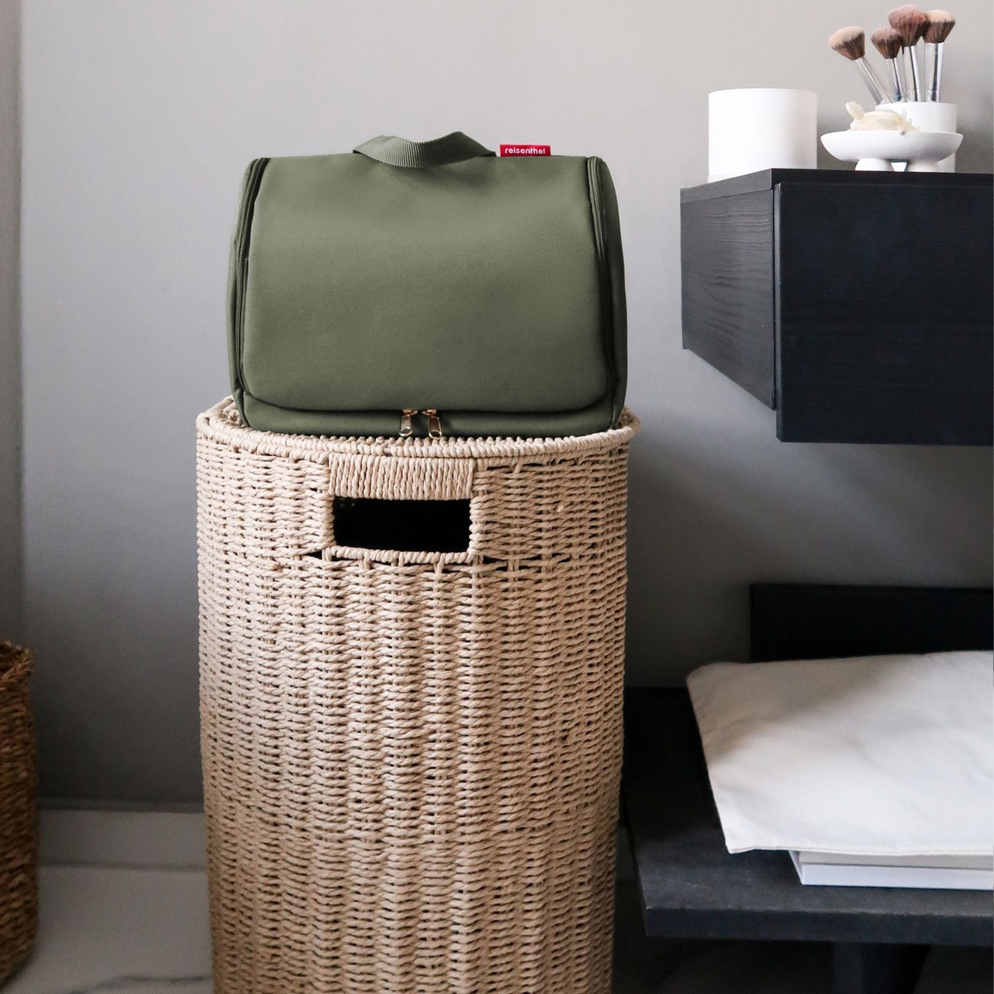 Green toiletry bag on woven laundry basket