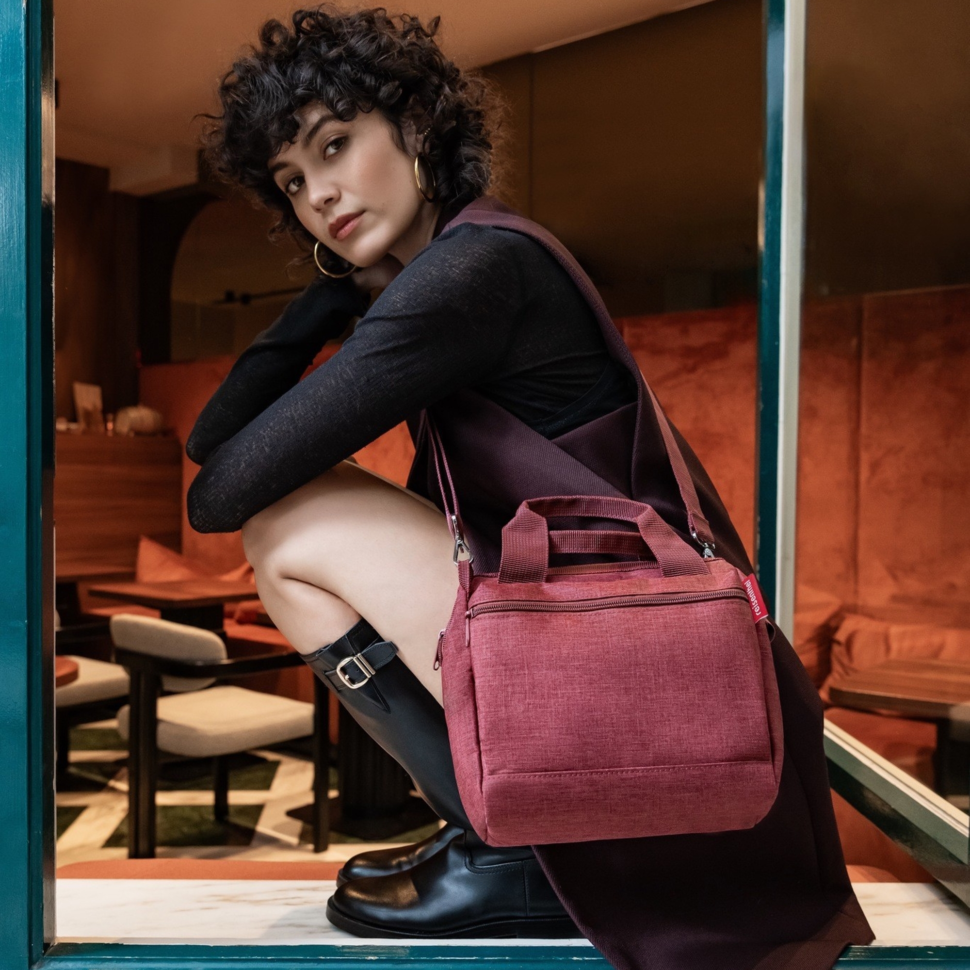 Woman with burgundy crossbody bag in café
