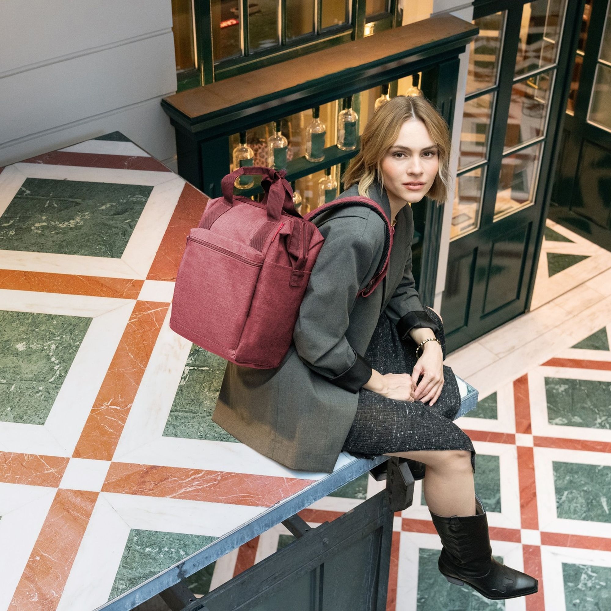 Woman with wine red city backpack indoors
