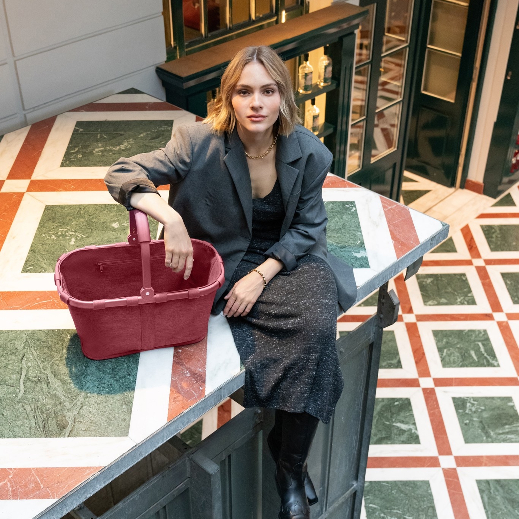 Woman with red shopping basket sitting on marble surface