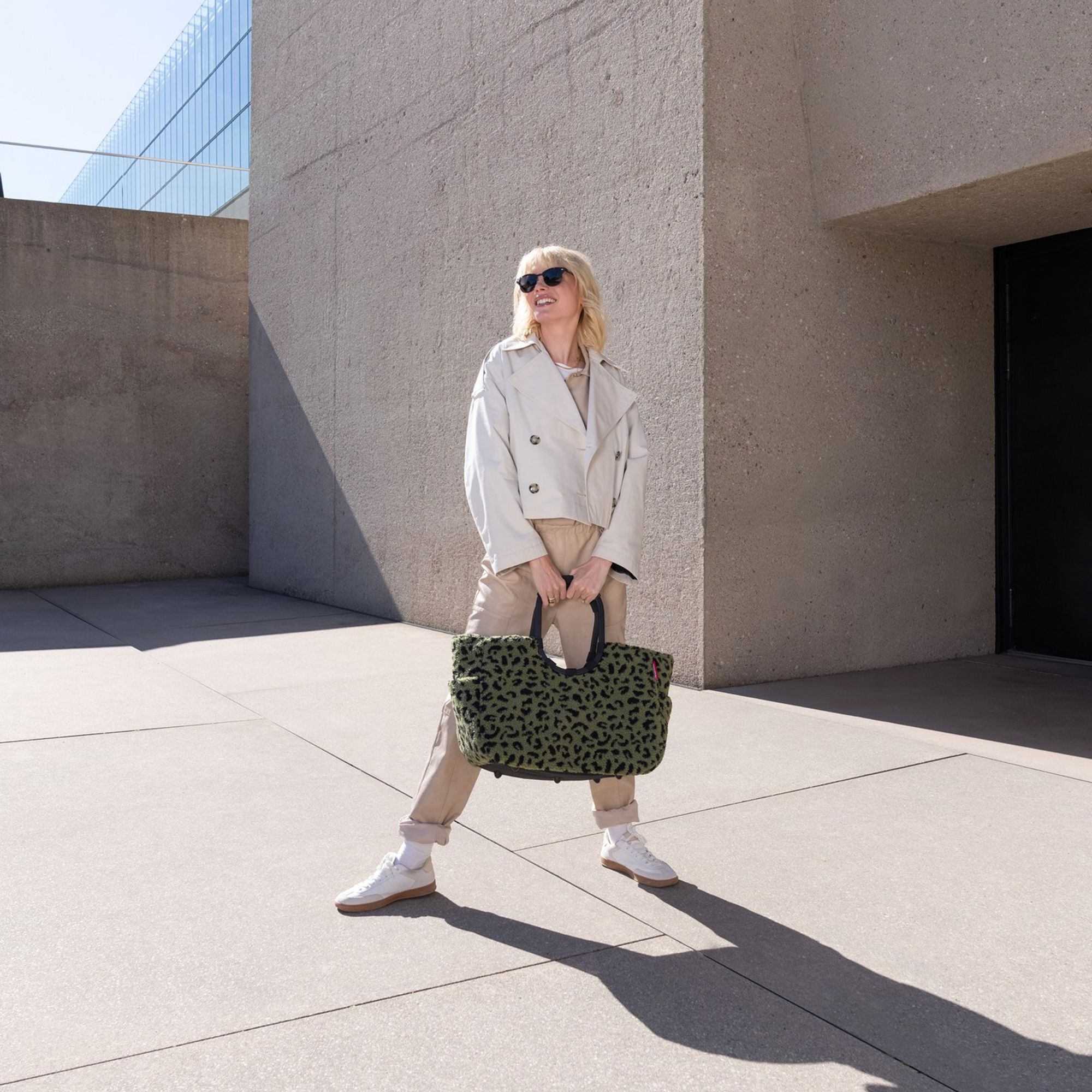 Woman wearing fashionable green shoulder bag with animal pri