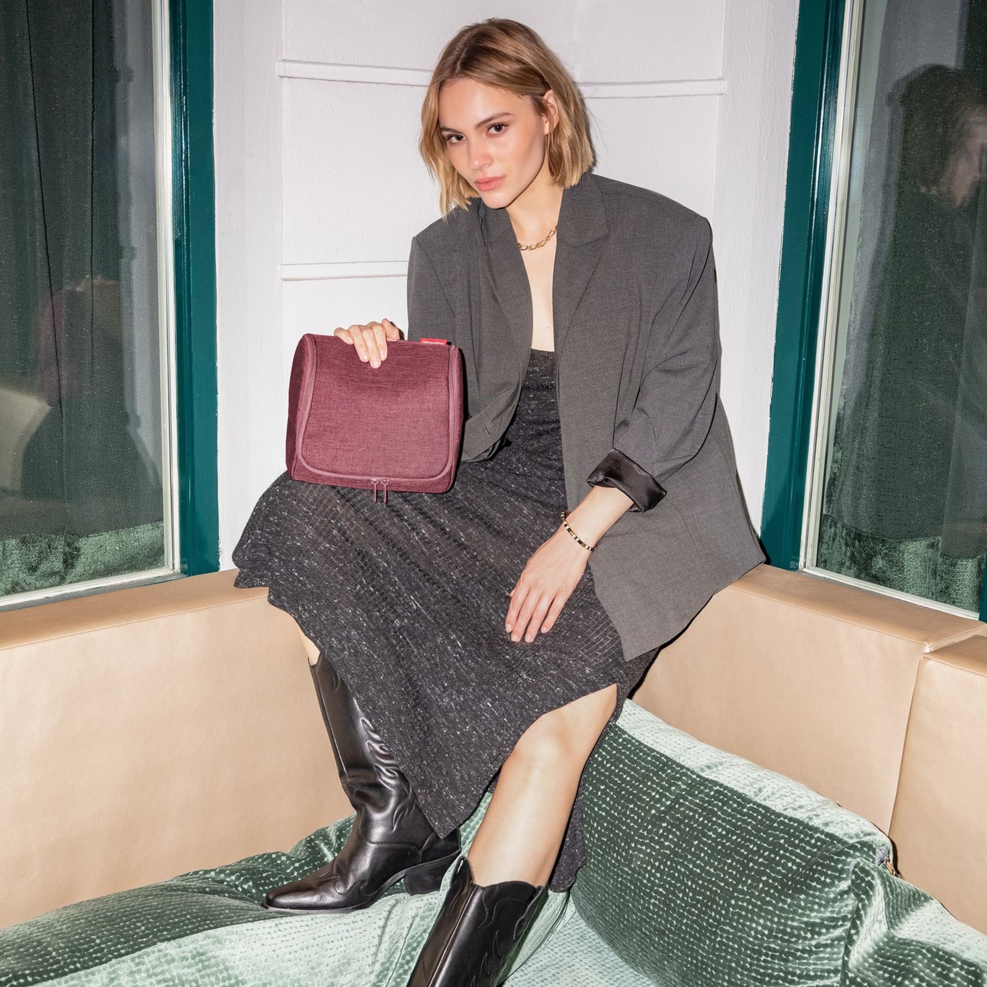 Woman wearing grey dress and blazer holding red bag