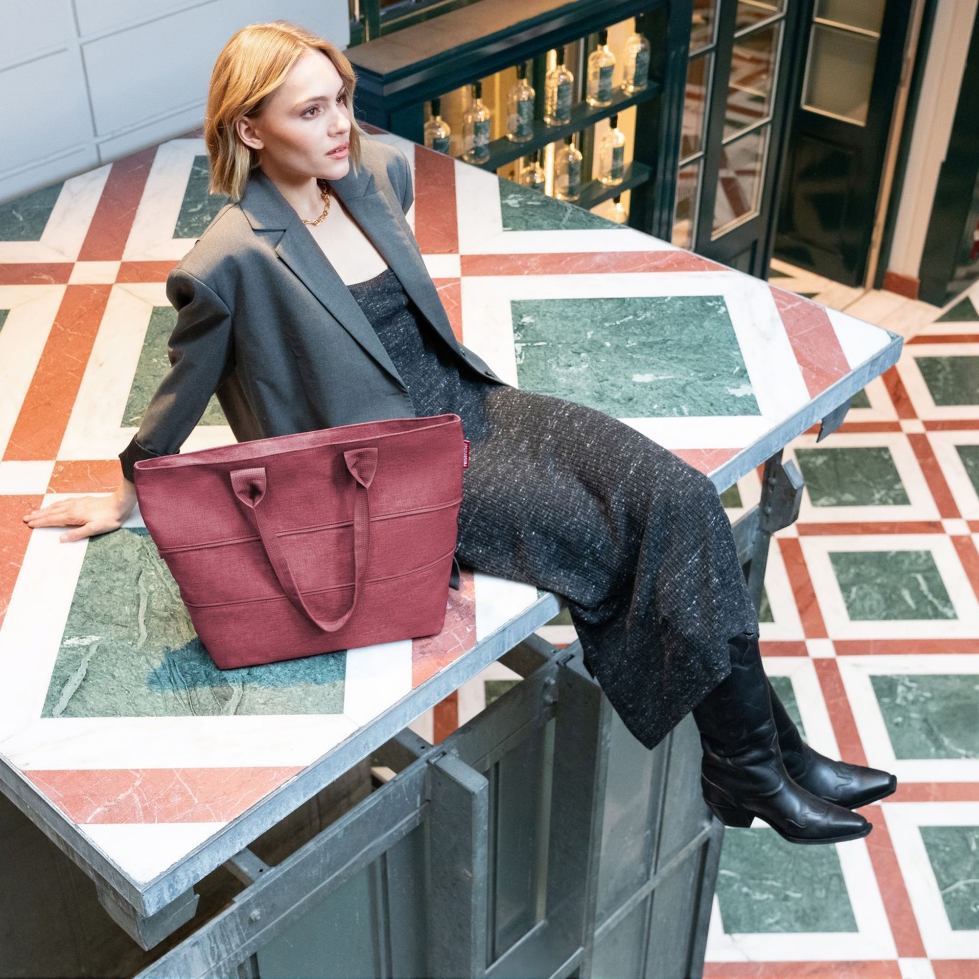 Red women’s shopper bag beside woman in blazer